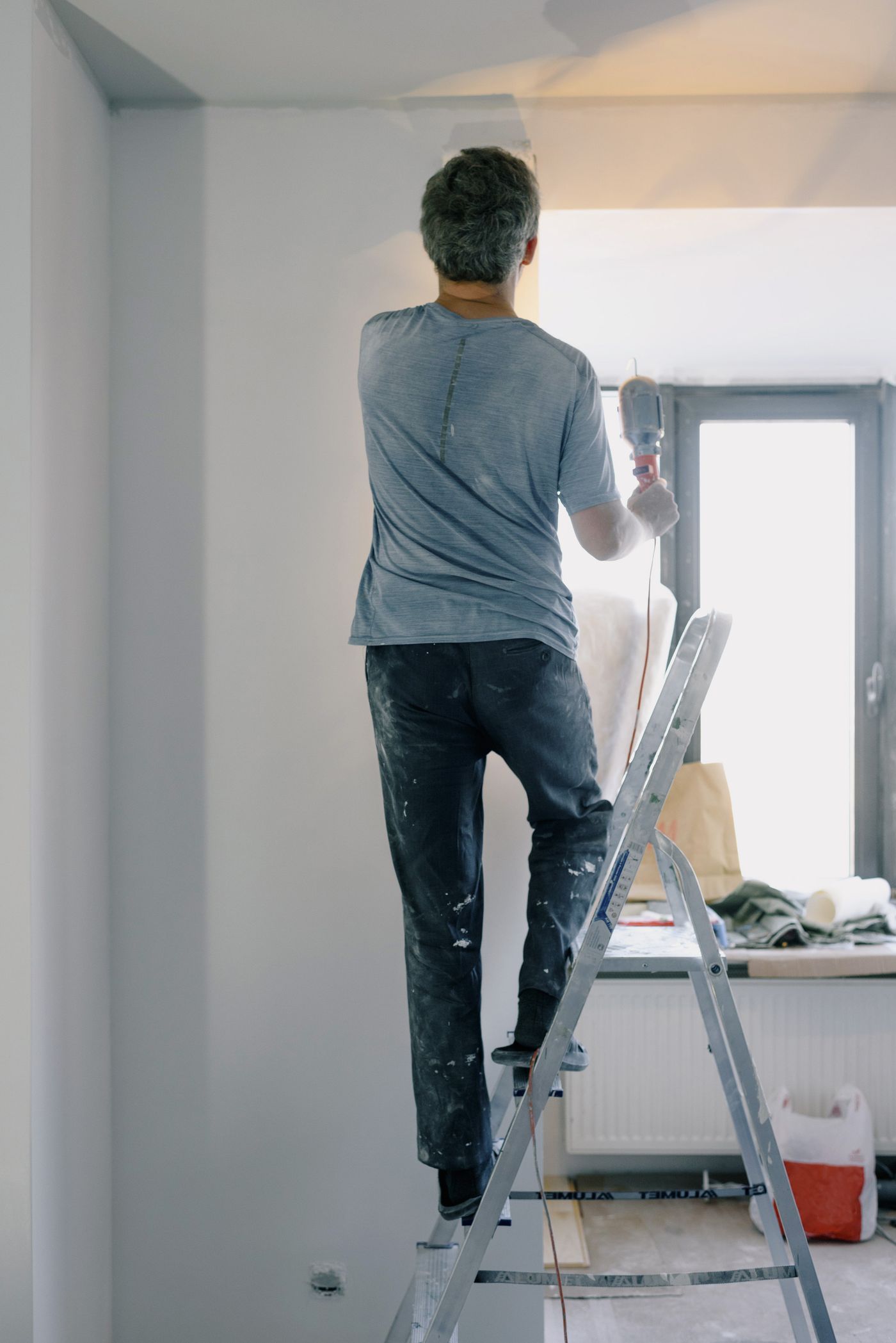 Profesional subido a una escalera haciendo una reparación en un piso